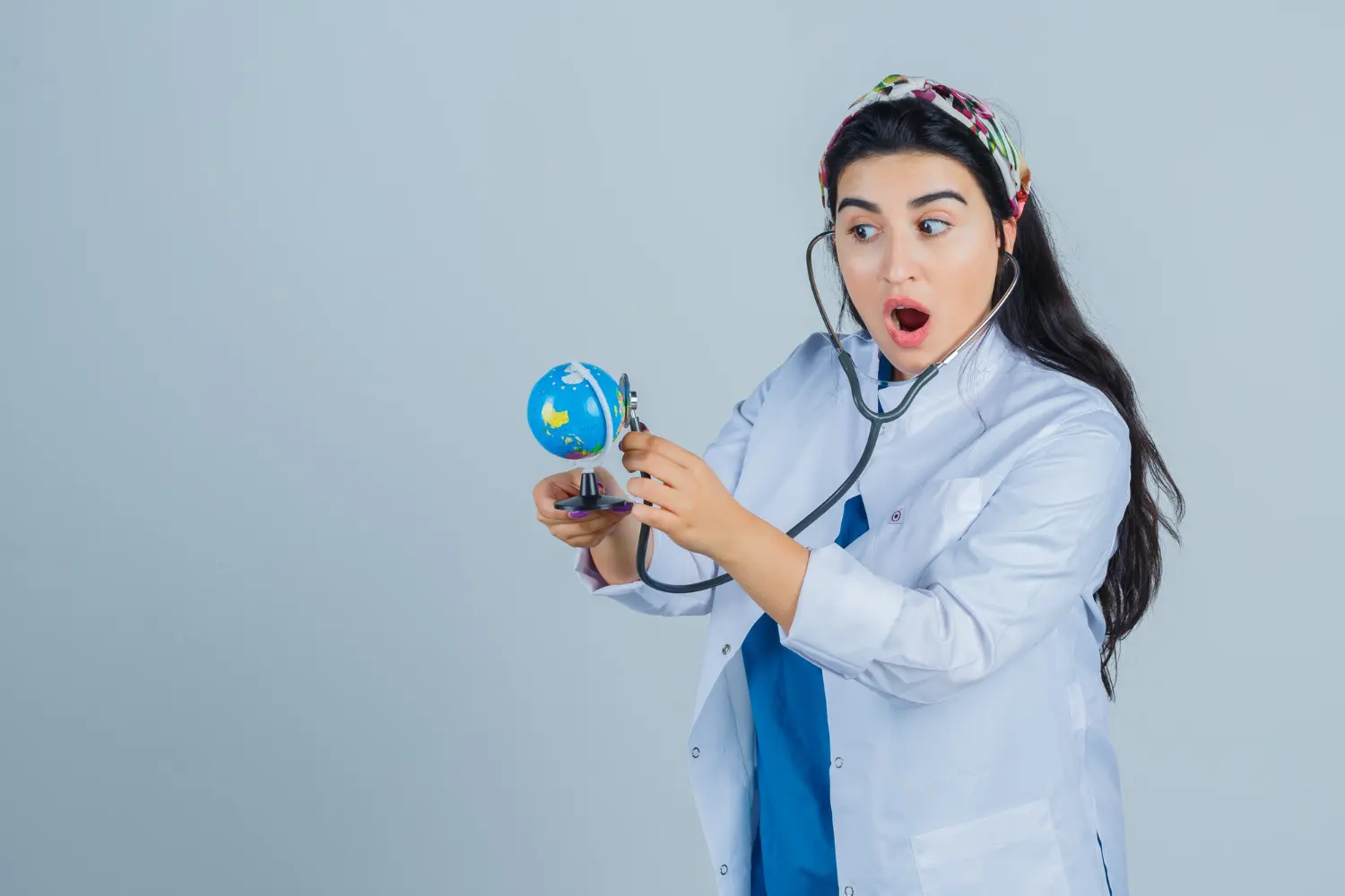 Female healthcare student using a stethoscope on a small globe, symbolizing global allied health science career insights.